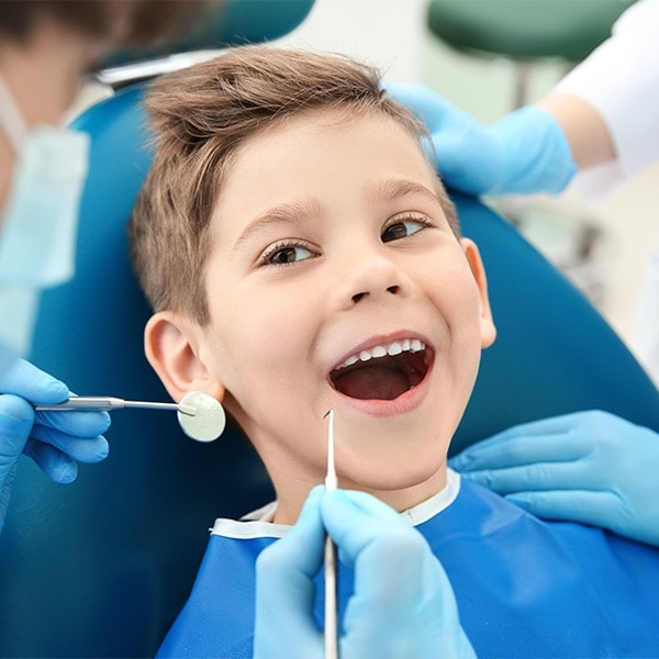Dentist examining little boy's teeth in clinic