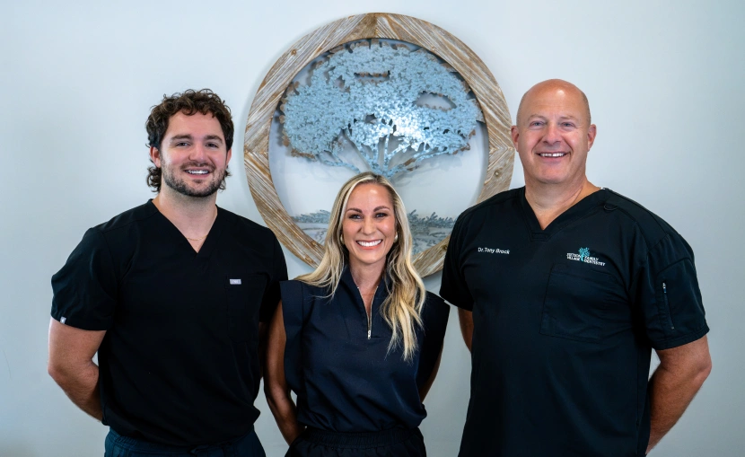 Three smiling Stetson Village Family Dentistry team members in black scrubs