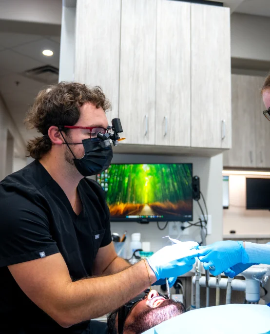 Stetson Village Family Dentistry dentist wearing loupes examines a patient during a dental cleaning