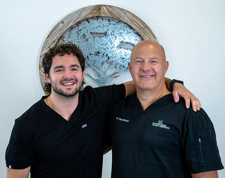 Two smiling dentists from Stetson Village Family Dentistry in black scrubs
