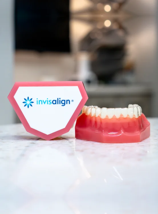 Invisalign clear aligner on a dental model beside an Invisalign sign at Stetson Village Family Dentistry in Peoria, AZ